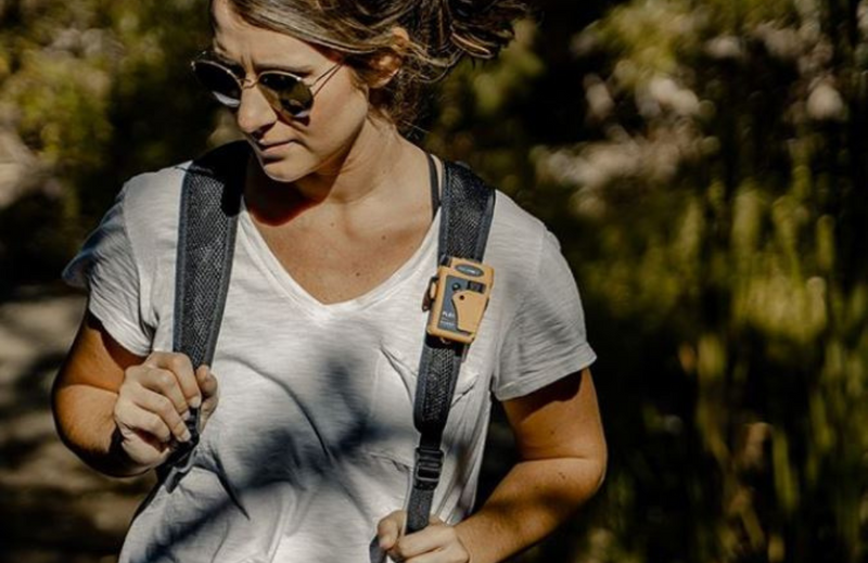 Person wearing a PLB clipped to backpack strap