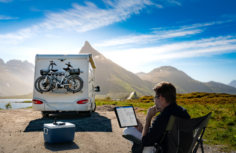 Camper using satellite Wi-Fi hotspot by a mountain